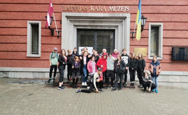 Bērni un skolotāji pie ēkas