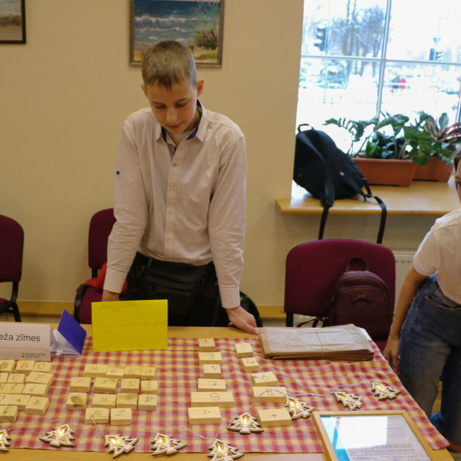 Zēns pie galda uz kura ir koka klucīši