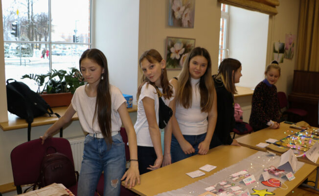 Meitenes pie galda pārdod rotas