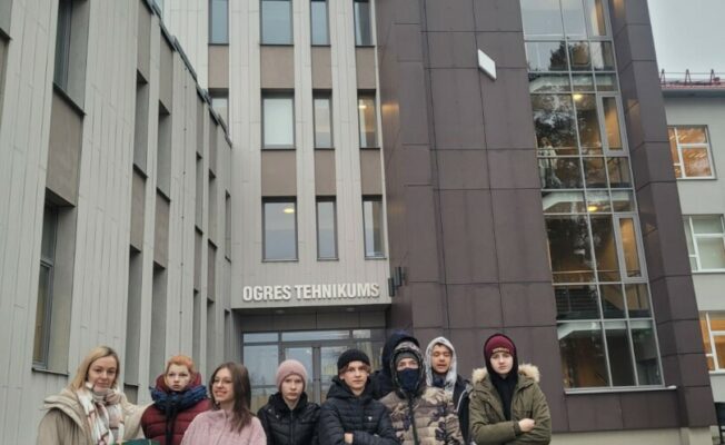 Bērni ar skolotāju pie skolas