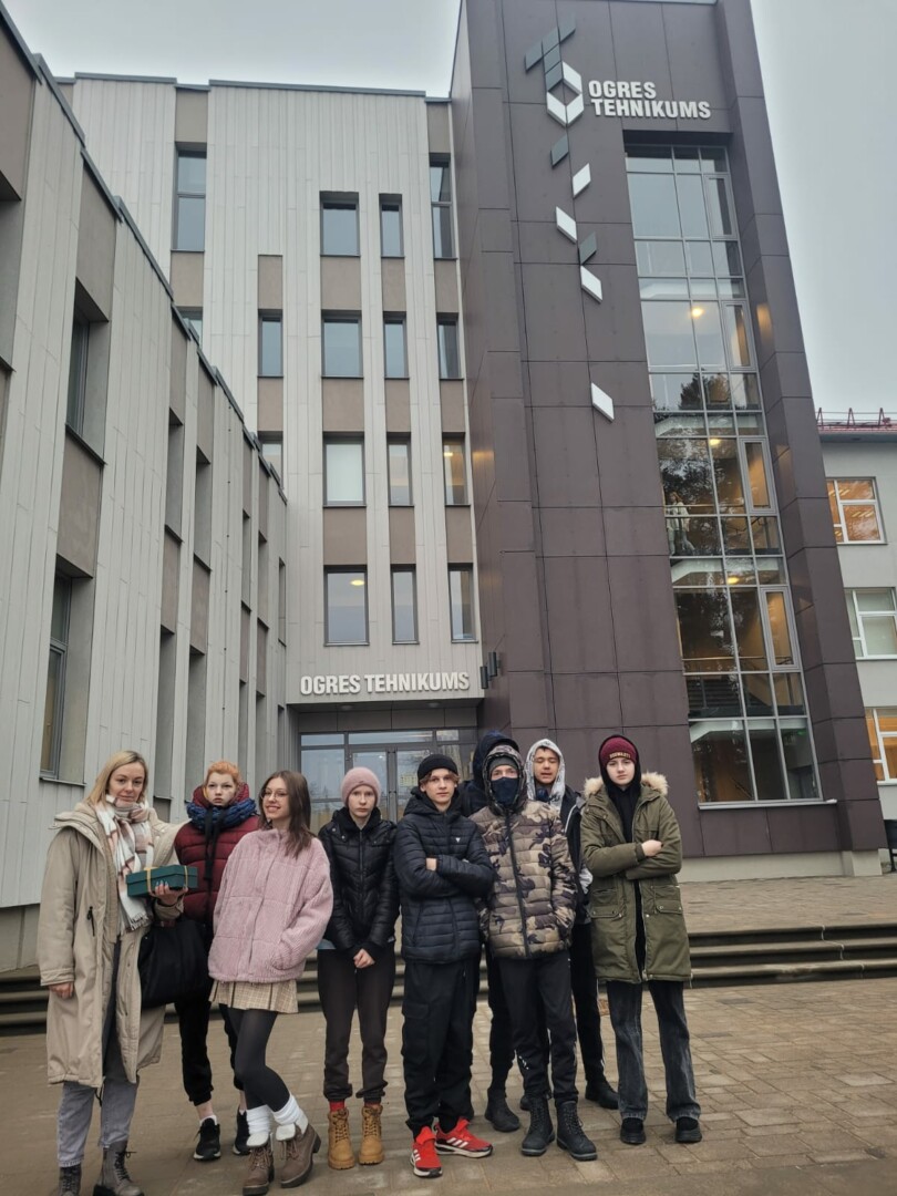 Bērni ar skolotāju pie skolas