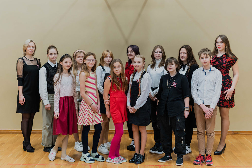 Bērni un skolotāja stāv sporta zālē