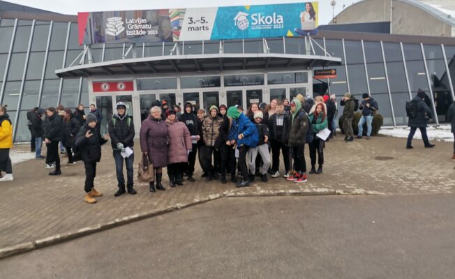 Pie ēkas stāv cilvēki