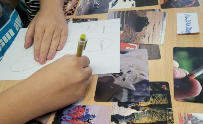 Bildes uz galdu un roka, kas raksta